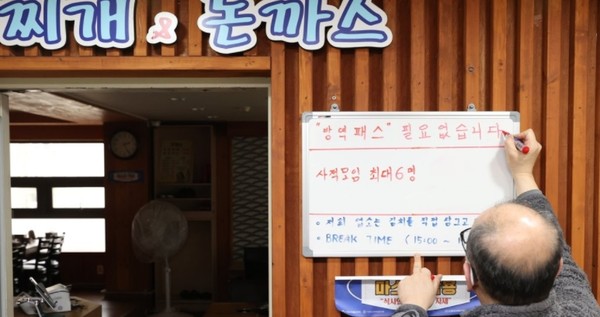 서울 종로구 한 식당에서 관계자가 방역패스 중단 안내문을 게시하는 모습./사진=연합뉴스