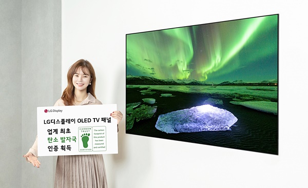 LG디스플레이 모델이 OLED TV 패널과 카본 트러스트의 탄소발자국 인증서를 소개하는 모습이다. /사진=LG디스플레이